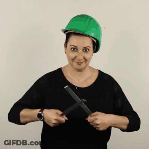 A Woman Wearing A Green Hard Hat Is Holding A Pair Of Scissors In Her Hands GIF