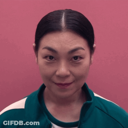 A Woman Wearing A Green Jacket Is Smiling And Looking At The Camera GIF
