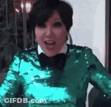 A Woman Wearing A Green Sequined Top And A Bow Tie Is Laughing . GIF