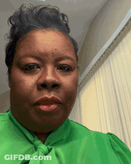 A Woman Wearing A Green Shirt And Tie Is Making A Funny Face GIF