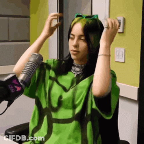 A Woman Wearing A Green Shirt Is Sitting In Front Of A Microphone GIF