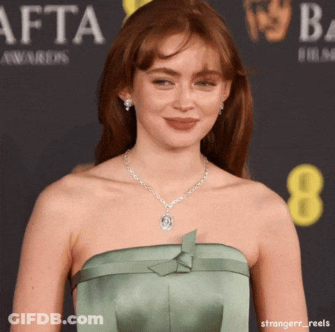 A Woman Wearing A Green Strapless Dress And A Necklace Is Standing In Front Of A Sign That Says Afta Awards GIF