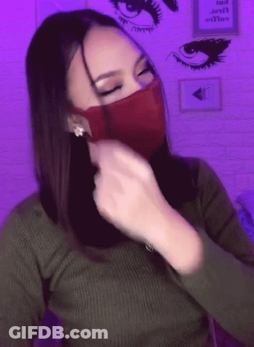 A Woman Wearing A Green Sweater And A Red Mask With A Purple Background GIF