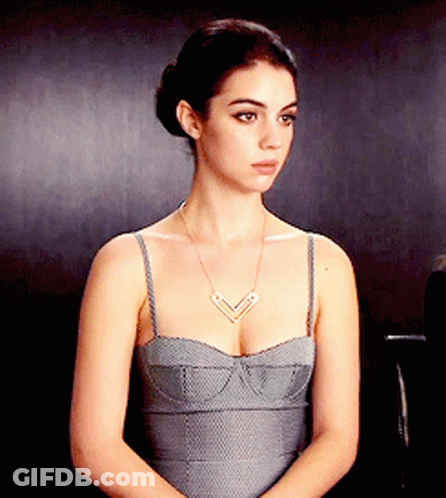 A Woman Wearing A Grey Dress And A Necklace GIF