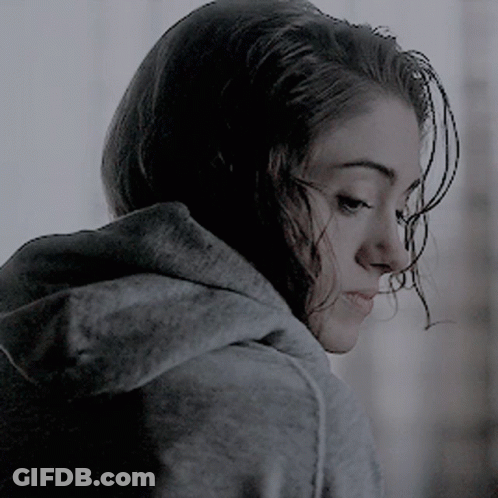 A Woman Wearing A Grey Hoodie Is Looking Down At Something GIF