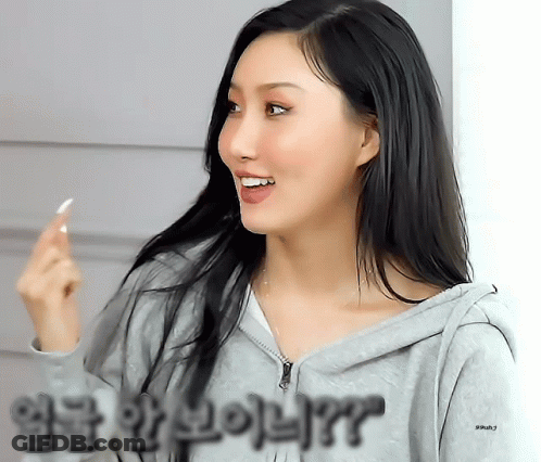 A Woman Wearing A Grey Hoodie With Korean Writing On The Sleeves GIF
