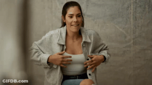 A Woman Wearing A Grey Jacket And White Tank Top GIF