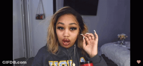 A Woman Wearing A Grey Sweatshirt With The Word Ucla On The Front GIF