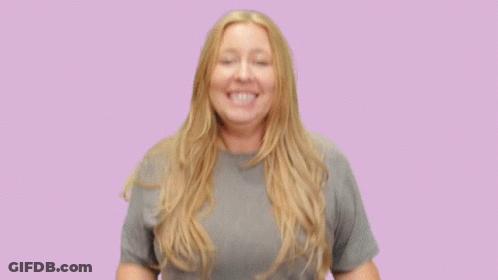 A Woman Wearing A Grey T-Shirt Is Smiling With Her Hands Outstretched GIF