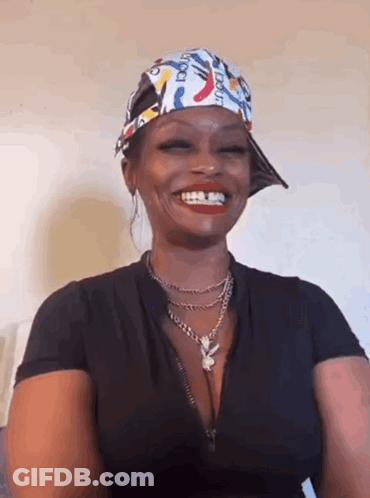 A Woman Wearing A Hat And A Necklace Is Smiling And Wearing A Bandana . GIF