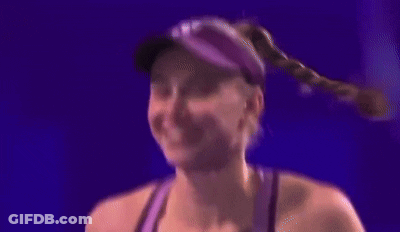 A Woman Wearing A Hat And A Purple Tank Top Is Smiling . GIF