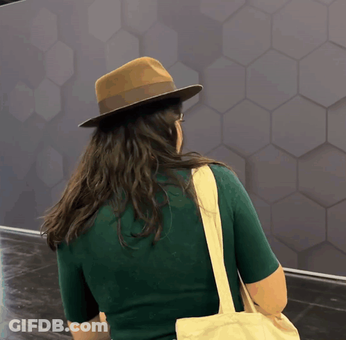 A Woman Wearing A Hat And Carrying A Bag GIF