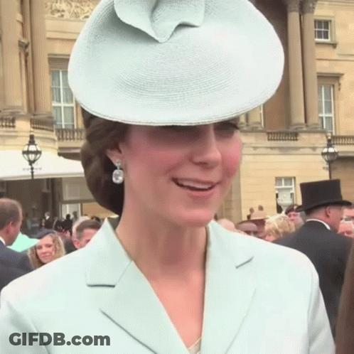 A Woman Wearing A Hat And Earrings Is Smiling GIF
