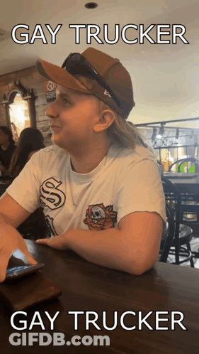 A Woman Wearing A Hat And Sunglasses Is Sitting At A Table With The Caption Gay Trucker Gay Trucker GIF