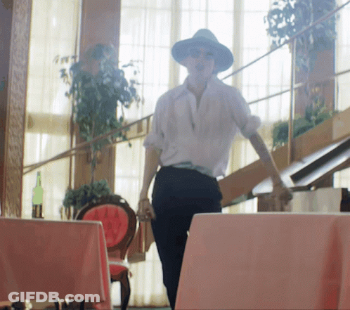 A Woman Wearing A Hat And Sunglasses Is Walking Down Stairs GIF