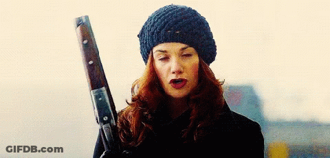A Woman Wearing A Hat Is Holding A Gun . GIF