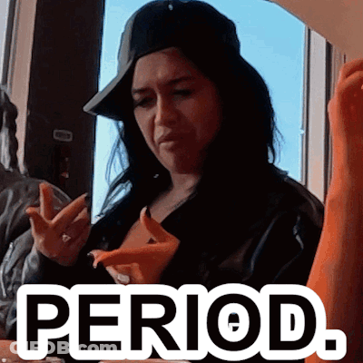 A Woman Wearing A Hat Is Sitting At A Table With The Word Period Written On It GIF