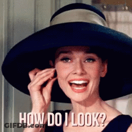 A Woman Wearing A Hat Is Smiling And Asking How Do I Look ? GIF