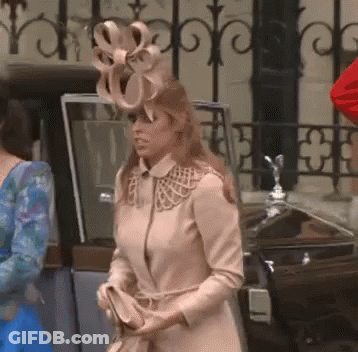 A Woman Wearing A Hat With A Bow On It Is Standing Next To A Car GIF