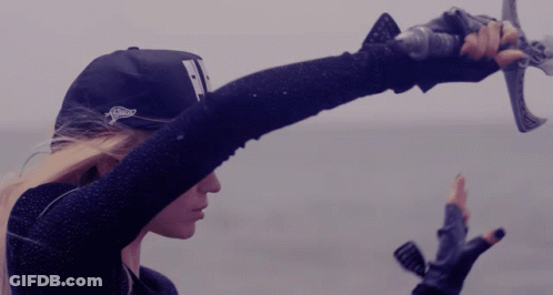 A Woman Wearing A Hat With The Letter T On It Is Holding A Sword GIF