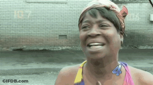 A Woman Wearing A Head Scarf And A Necklace With The Number 44 On It Is Smiling . GIF