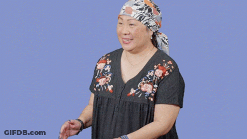 A Woman Wearing A Head Scarf Is Standing In Front Of A Sign That Says Oops GIF