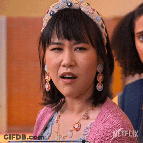A Woman Wearing A Headband And Earrings Is Making A Funny Face GIF