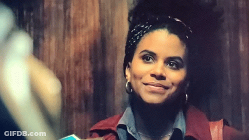 A Woman Wearing A Headband And Earrings Is Smiling . GIF