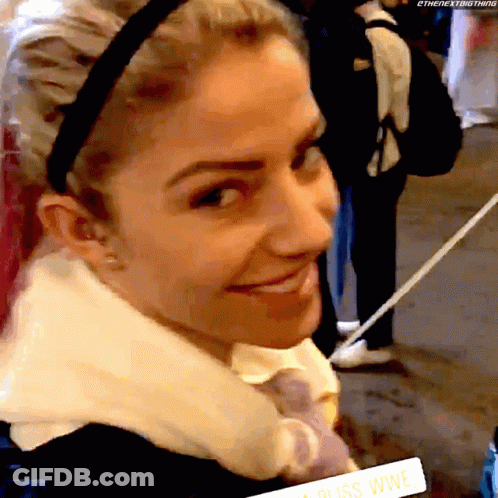 A Woman Wearing A Headband Is Smiling And Holding A Sign That Says ' Bliss Wwe ' On It GIF