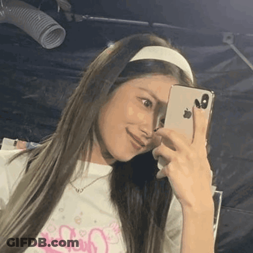 A Woman Wearing A Headband Is Taking A Selfie With Her Cell Phone . GIF