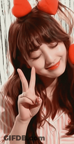 A Woman Wearing A Headband With Hearts On It Is Giving A Peace Sign GIF