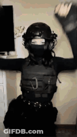 A Woman Wearing A Helmet And A Mask Is Standing In Front Of A Television . GIF