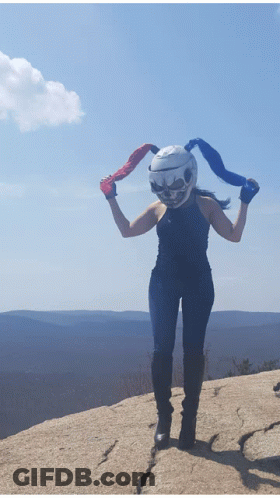 A Woman Wearing A Helmet With A Skull On It Stands On A Rock GIF