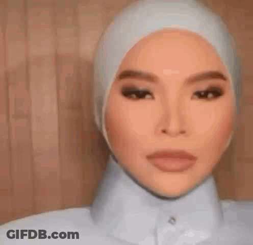 A Woman Wearing A Hijab And A White Shirt Is Smiling . GIF