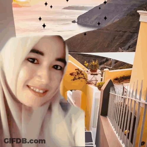 A Woman Wearing A Hijab Is Smiling In Front Of A Painting Of A Landscape GIF
