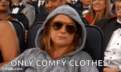 A Woman Wearing A Hoodie And Sunglasses Is Sitting In A Theater . GIF