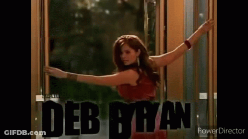A Woman Wearing A Hoodie With The Name Debby Ryan On It Is Standing In A Room . GIF
