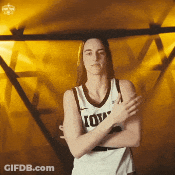 A Woman Wearing A Iowa Jersey Is Standing With Her Arms Crossed GIF