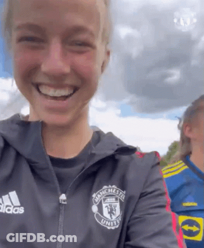 A Woman Wearing A Jacket That Says Manchester United On It GIF