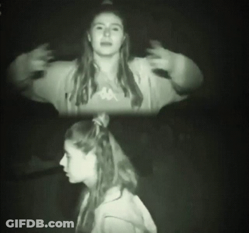A Woman Wearing A Kappa Sweatshirt Stands In The Dark GIF