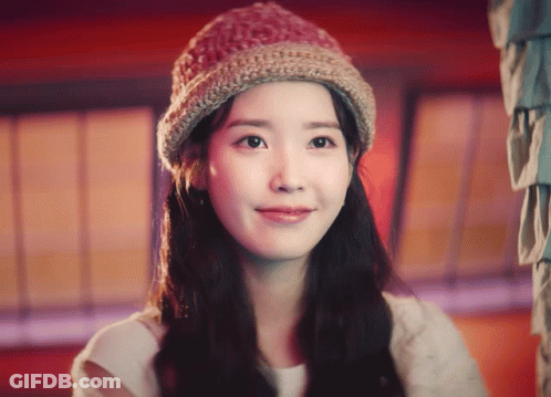 A Woman Wearing A Knitted Hat Looks At The Camera And Smiles GIF