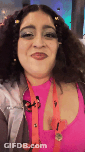 A Woman Wearing A Lanyard With A Butterfly On It And A Pink Top With A Butterfly Pin GIF