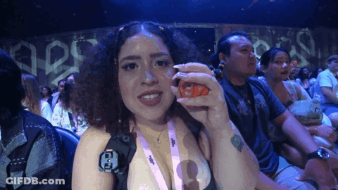 A Woman Wearing A Lanyard With The Letter E On It Holds Something In Her Hand GIF