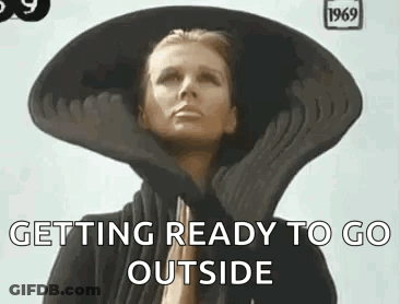 A Woman Wearing A Large Hat And Gloves Is Getting Ready To Go Outside . GIF