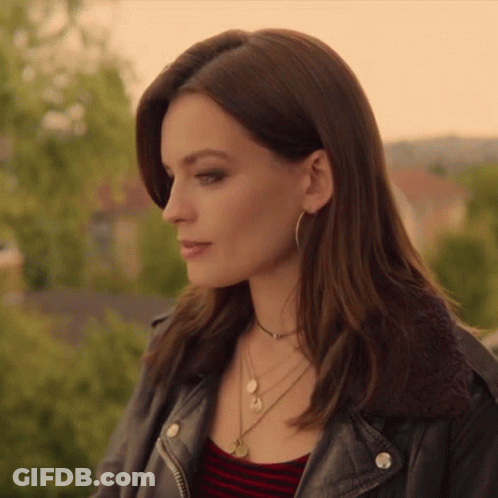 A Woman Wearing A Leather Jacket And A Necklace Looks To The Side GIF