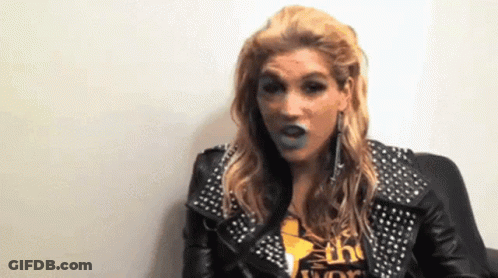 A Woman Wearing A Leather Jacket With Studs And A Shirt That Says The World GIF