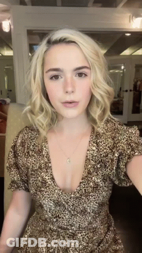 A Woman Wearing A Leopard Print Dress Is Standing In Front Of A Mirror GIF