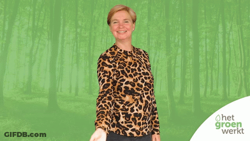 A Woman Wearing A Leopard Print Shirt Is Standing In Front Of A Green Forest GIF