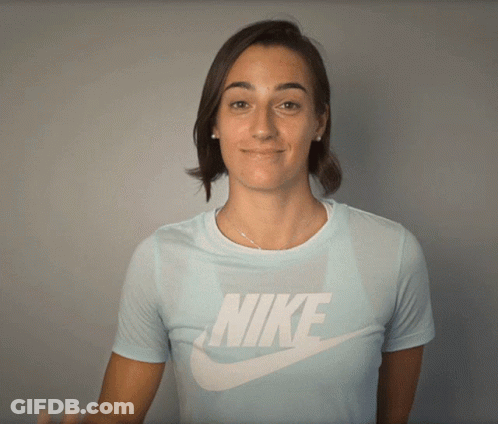 A Woman Wearing A Light Blue Nike Shirt Smiles GIF