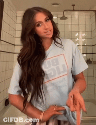 A Woman Wearing A Light Blue T-Shirt With The Word Big On It Is Standing In A Bathroom GIF